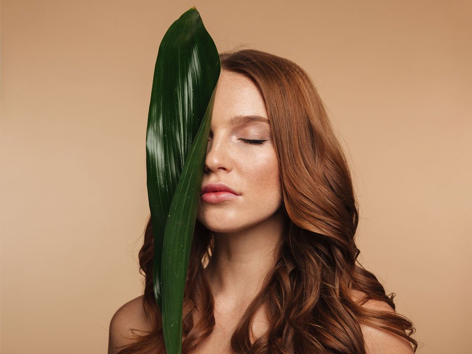 Mujer con una hoja en la cara, preparándonse para una rutina de belleza básica